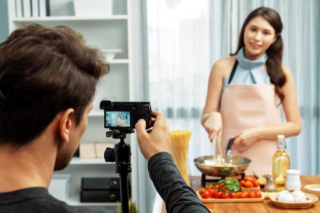 Photo cameraman recording to woman in chef influencer cooking spaghetti postulate