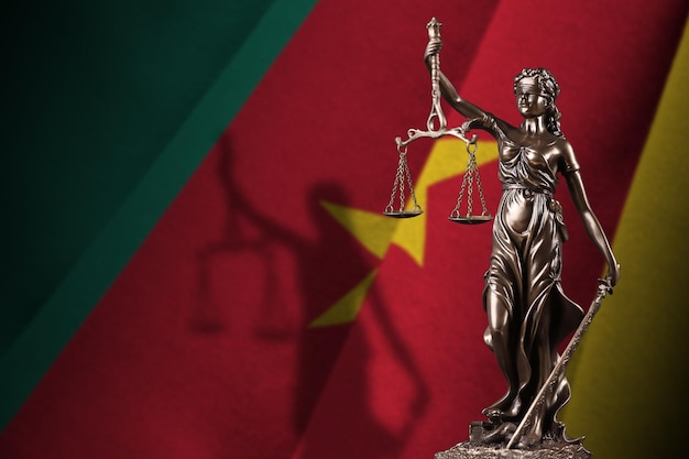 Cameroon flag with statue of lady justice and judicial scales in dark room Concept of judgement and punishment