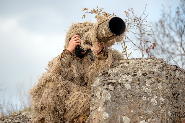 Camouflage wildlife photographer in the ghillie suit working in the wild