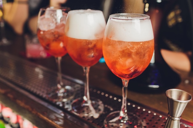 Campari tonic alcoholic cocktail with red bitter tonic lime and ice Old wooden table background bar tools selective focus All names refer to cocktails not trademarks