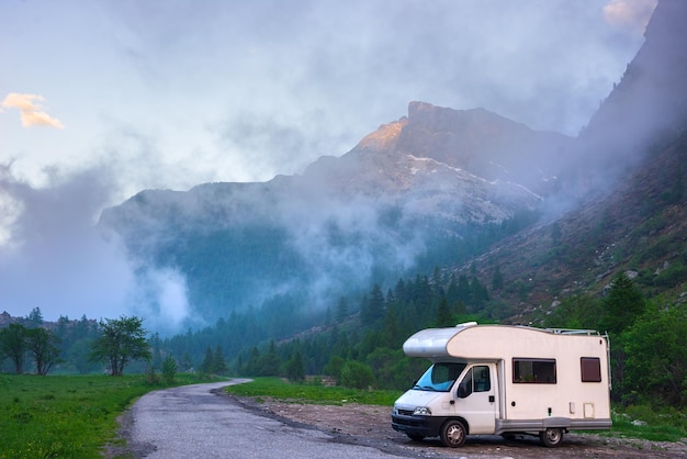 Camper van in the mountains the Alps Piedmont Italy Sunset dramatic sky and clouds unique highlands and rocky mountains landscape alternative vanlife vacation concept