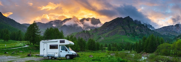 Camper van in the mountains the Alps Piedmont Italy Sunset dramatic sky and clouds unique highlands and rocky mountains landscape alternative vanlife vacation concept