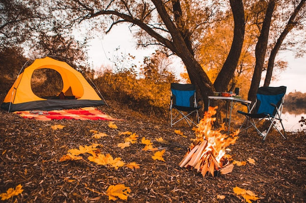 Camping autumn place with bonfire and portable chairs no people.