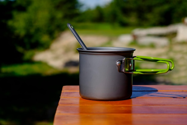 Camping pot with spoon on a wooden table