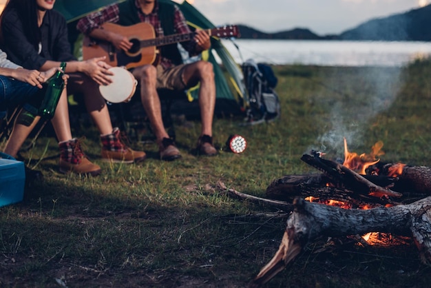 Camping tent camp in nature happy friends group night party bonfire and playing guitar together in summer at nature forest