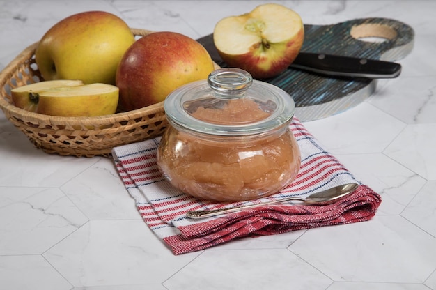 A can of applesauce and apples in a wicker plate on a light background an Apple with a knife on a wooden cutting BoardHorizontal orientation