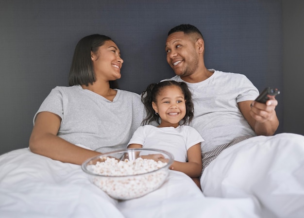 Can I press play now Shot of a young couple sitting in bed with their daughter and getting ready to watch a movie