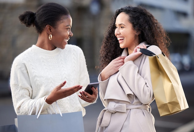 Can you believe that he said that. Shot of two friends using a smartphone during a day of shopping.