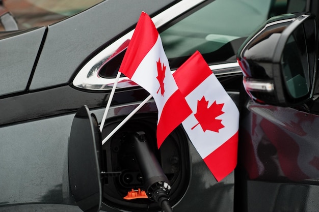 Canada flag ecological car concept. Plugging a power supplier, charging modern automobile.