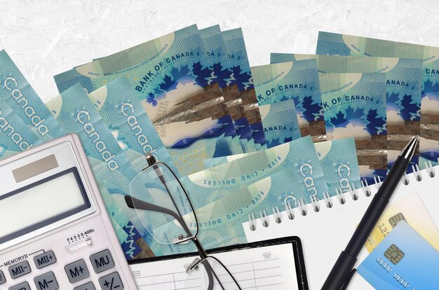 Canadian dollars bills and calculator with glasses and pen