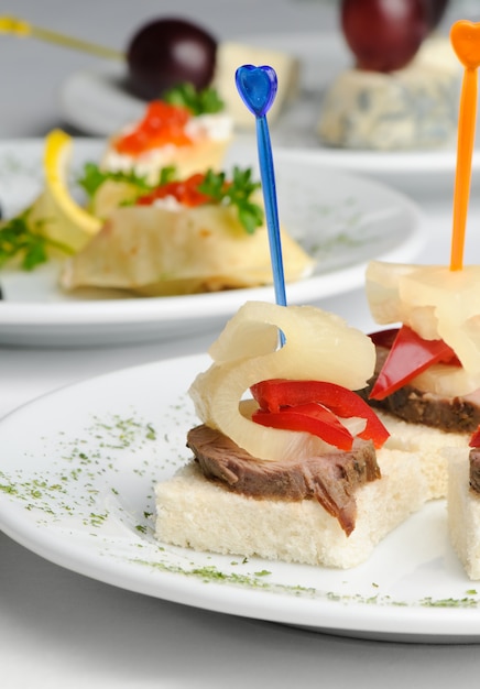 Canape with baked meat and slice of pineapple and red pepper, served on plate