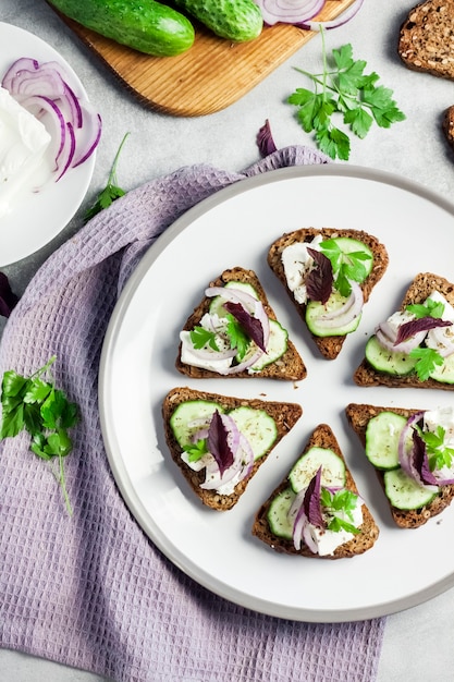 Canapes with toasted bread with sunflower and flax seeds, feta cheese, cucumber and onion