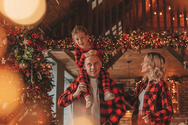 Photo candid authentic cute happy family in red plaid pajamas spends time together at lodge xmas decorated