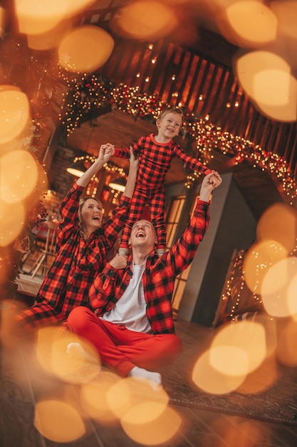 Photo candid authentic cute happy family in red plaid pajamas spends time together at lodge xmas decorated