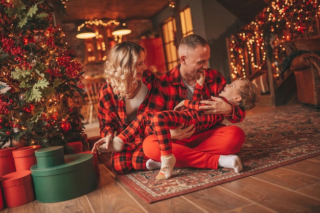 Photo candid authentic cute happy family in red plaid pajamas spends time together at lodge xmas decorated