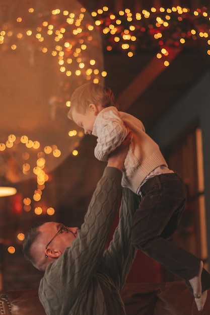 Candid authentic happy dad playing with little son fooling around at wooden lodge Xmas decorated