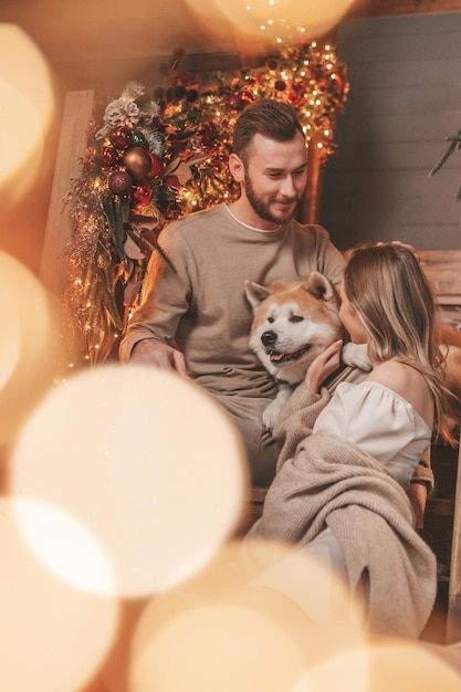 Candid authentic happy married couple spends time together with japanese dog at Xmas lodge