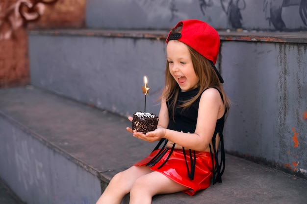 Candid girl is holding cupcake with burning candle in shape of star