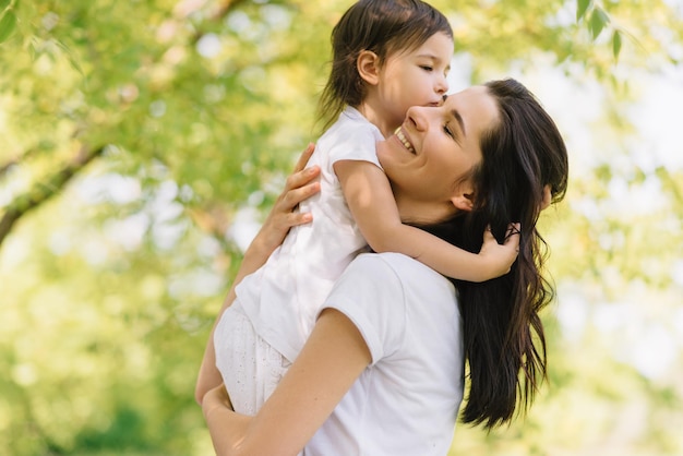 Candid shot of cheerful beautiful mother and her cute daughter playing outdoors holding each other Mom and her pretty kid playing in the park together Portrait of good relationship in family