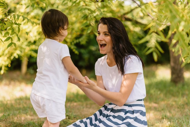 Candid shot of happy beautiful mother and her cute kid playing outdoors holding each other show the love Mom and her pretty kid play in the park Portrait of good relationship in family Motherhood