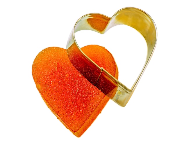 Candied fruit jelly apricot in the form of heart on isolated background with iron form