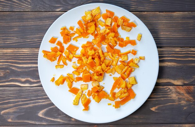 Candied fruit on the plate. Dried homemade oranges. Wooden background.