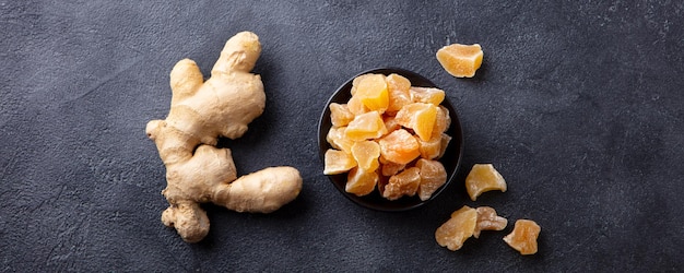 Candied ginger in black bowl on dark stone background Top view Copy space