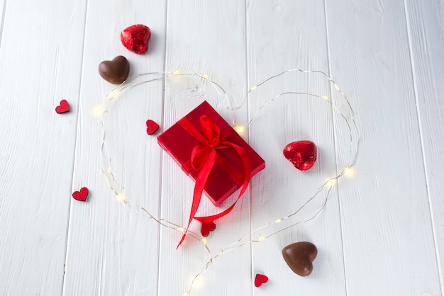 Candies hearts and gift box on wooden board,