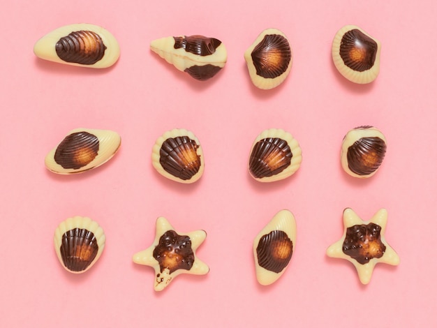 Candies made of white and dark chocolate stacked on pink 