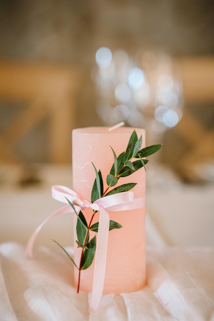 Candle are decorated with pink bow ribbon and greens stand on the festive table covered with a tablecloth flat lay top view Wedding inspiration Close up Artwork Decor Details