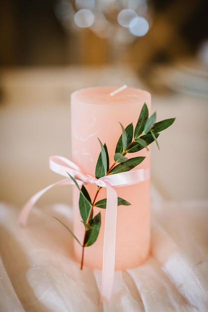 Candle are decorated with pink bow ribbon and greens stand on the festive table newlyweds covered with a tablecloth flat lay top view Wedding inspiration Close up Artwork Decor Details