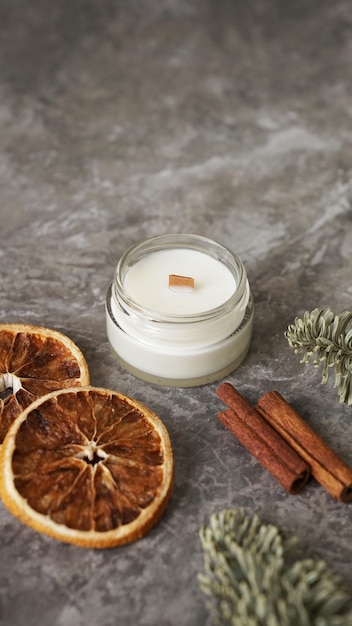 Candle in a glass with slices of orange cinnamon sticks and fir branches