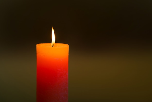 Candle light with flame on dark soft background