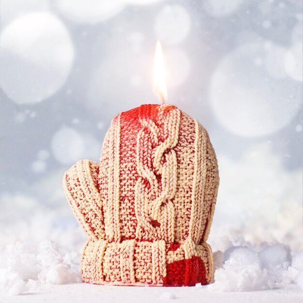 Candle red mitten on a white blurred background.