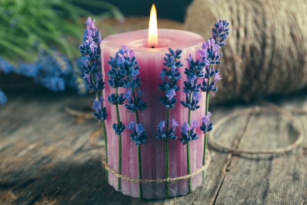 Candle with lavender flowers on table close up