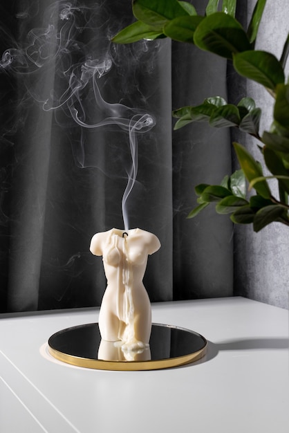 Candle in woman torso shape burning in grey modern interior room atmosphere and smoke after candle