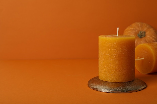 Candles golden stand and pumpkin on orange background space for text