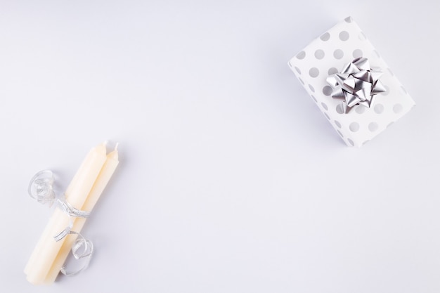 Candles with silver ribbon and gift . Top view.