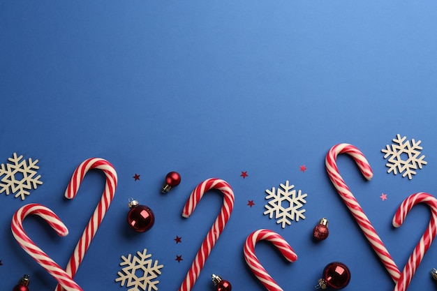 Candy canes Christmas balls and snowflakes on blue background flat lay Space for text