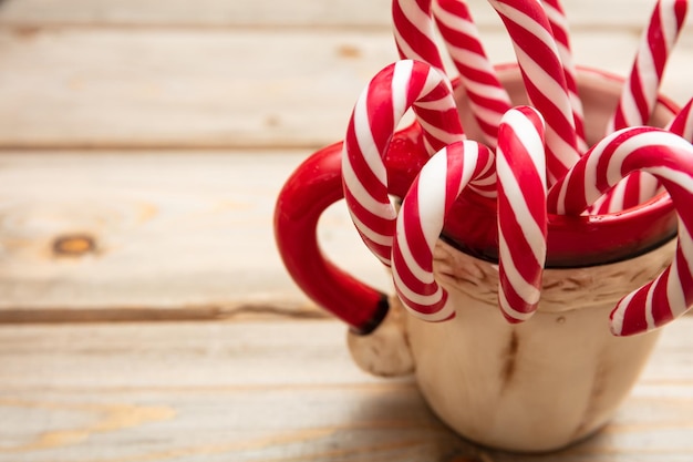 Candy canes in a christmas cup wooden background copy space