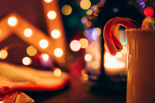 Candy canes in a cup on blurred Christmas lights background