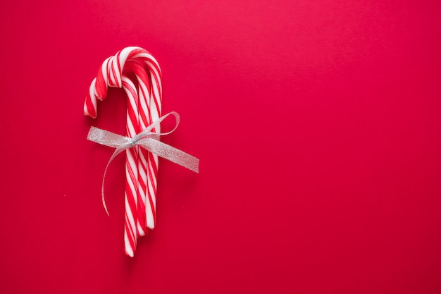 Candy canes with silver bow on red background for greeting card on Christmas and New Year 