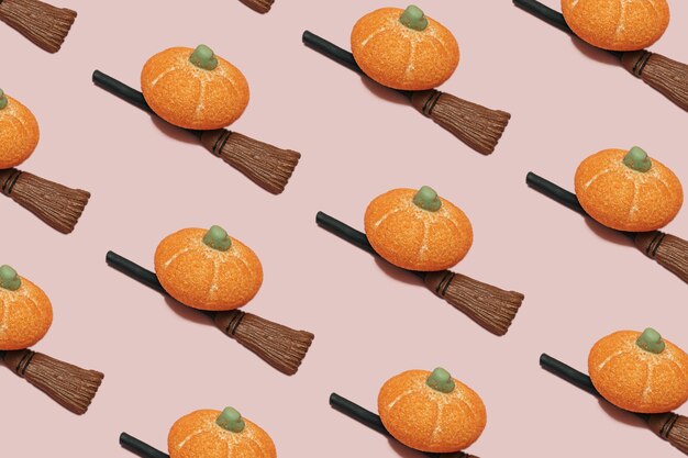 Candy sugar orange pumpkin on a witch broom stick on pink background with copy space Minimal halloween holiday celebration horror concept Autumn party pattern idea