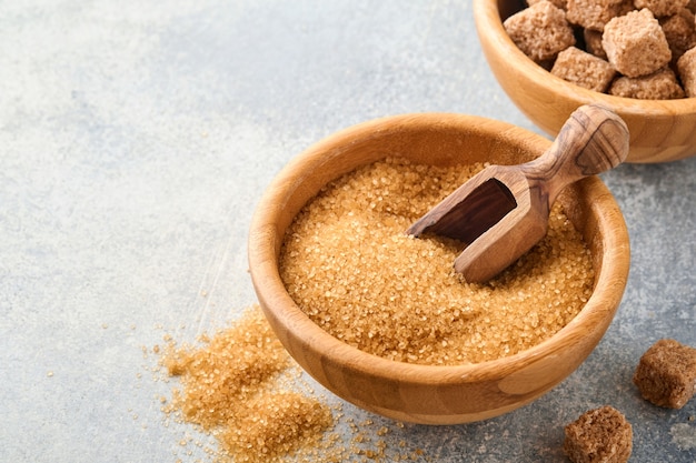 Cane sugar cube in bamboo bowl on gray table concrete background. Top view.