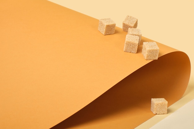 Cane sugar cubes on brown background, trend color place copy, roll paper, beige background