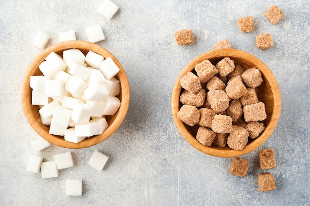 Cane sugar and white sugar cube in bamboo bowl on gray table concrete