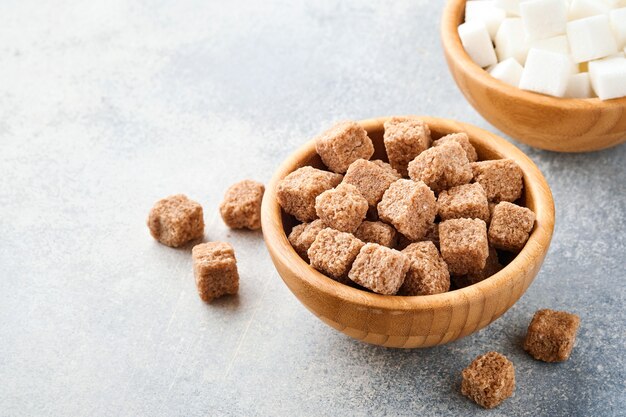 Cane sugar and white sugar cube in bamboo bowl on gray table concrete