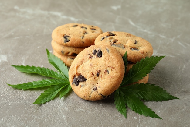 Cannabis cookies and leaves on gray textured table