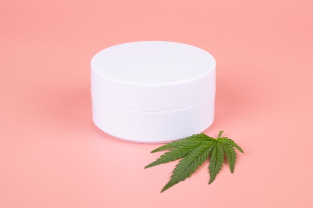 Cannabis cosmetics natural marijuana cream and green leaf on beauty pink background