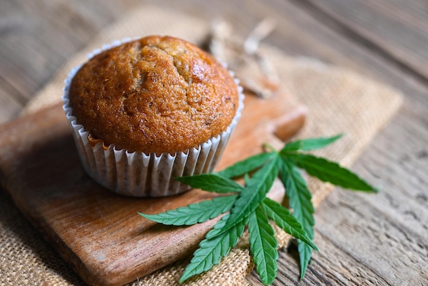 Cannabis food cake with cannabis leaf marijuana herb on wooden background delicious sweet dessert cupcakes with hemp leaf plant THC CBD herbs food snack and medical concept